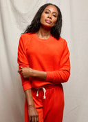 Woman wearing an orange outfit against a plain background